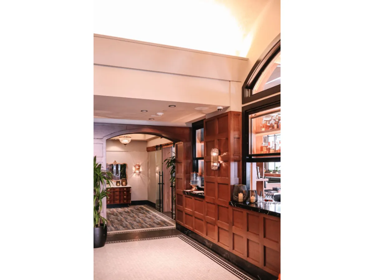 A stylish bar area framed by rich wood paneling, an ornate chandelier, and plush seating. The ambiance is warm and welcoming, ideal for unwinding with cocktails or engaging in intimate conversations after a day of city adventures.